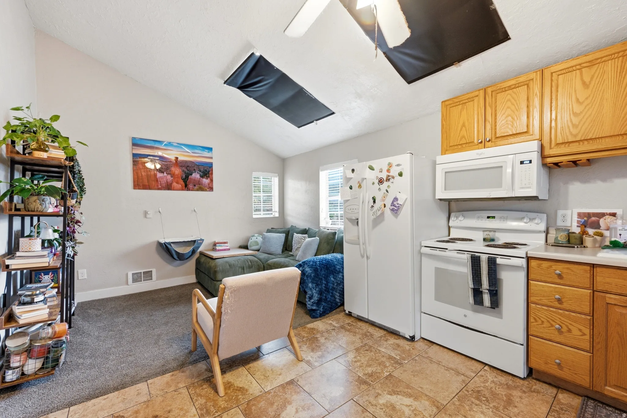Kitchen with light wood-finish cabinetry, white appliances, and tiled flooring