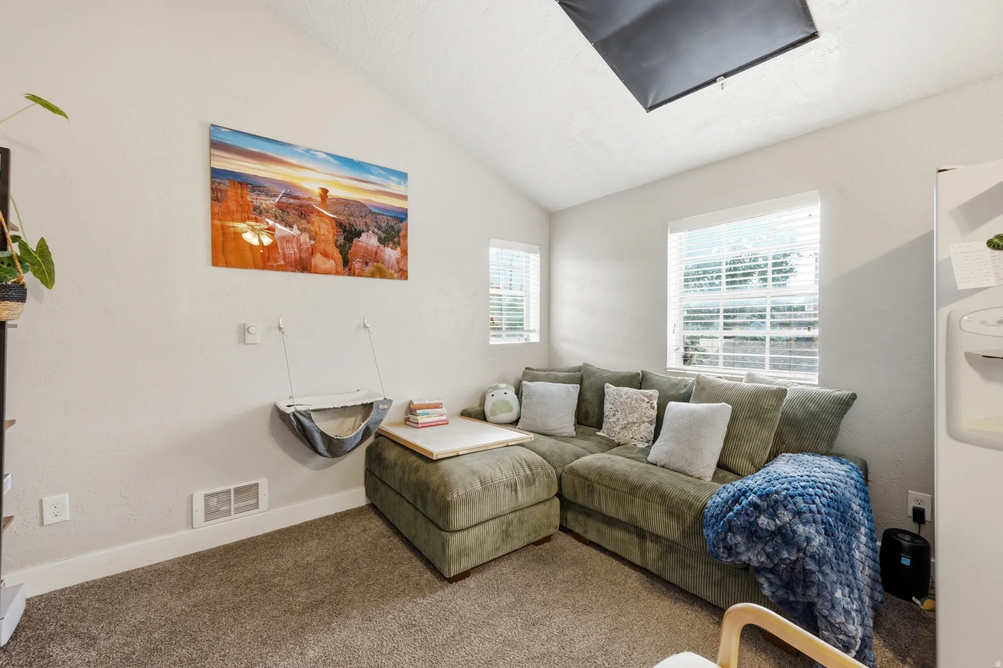 Vaulted ceiling with a skylight, dual windows with blinds, and light gray wall paint