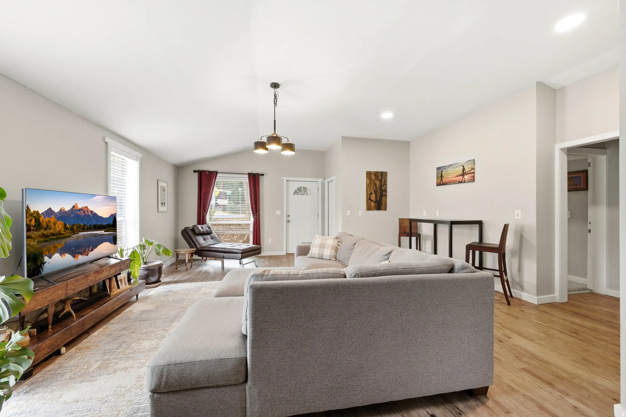 Spacious open-concept living area featuring hardwood flooring, recessed ceiling lighting, and a gray upholstered sectional sofa