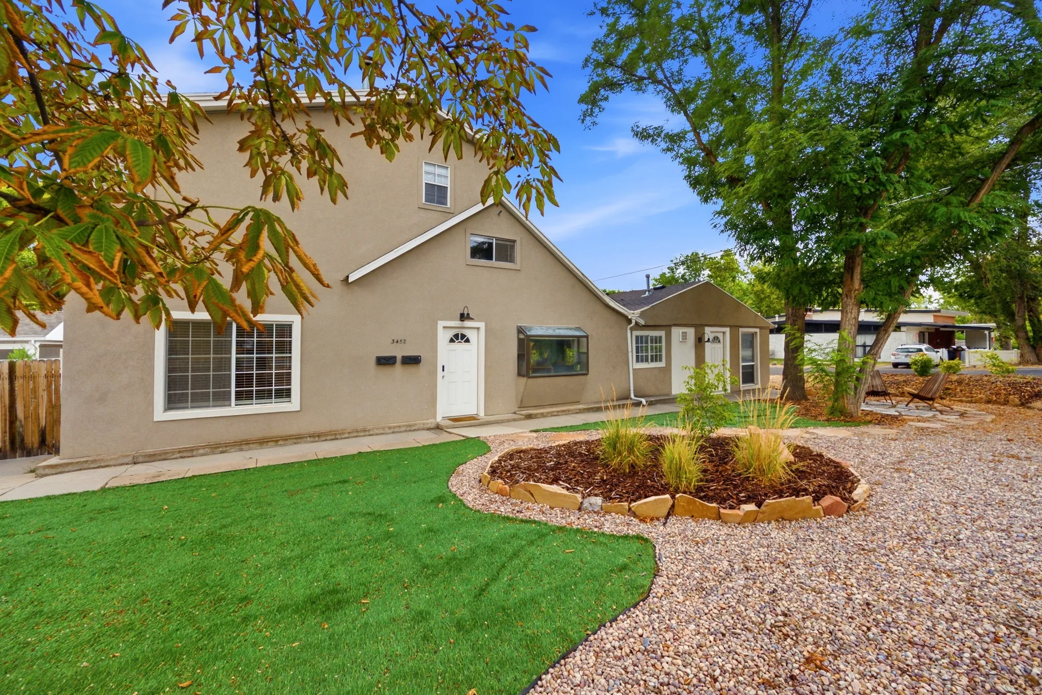 Stucco exterior with multiple windows, a white entry door, and an extended bay window