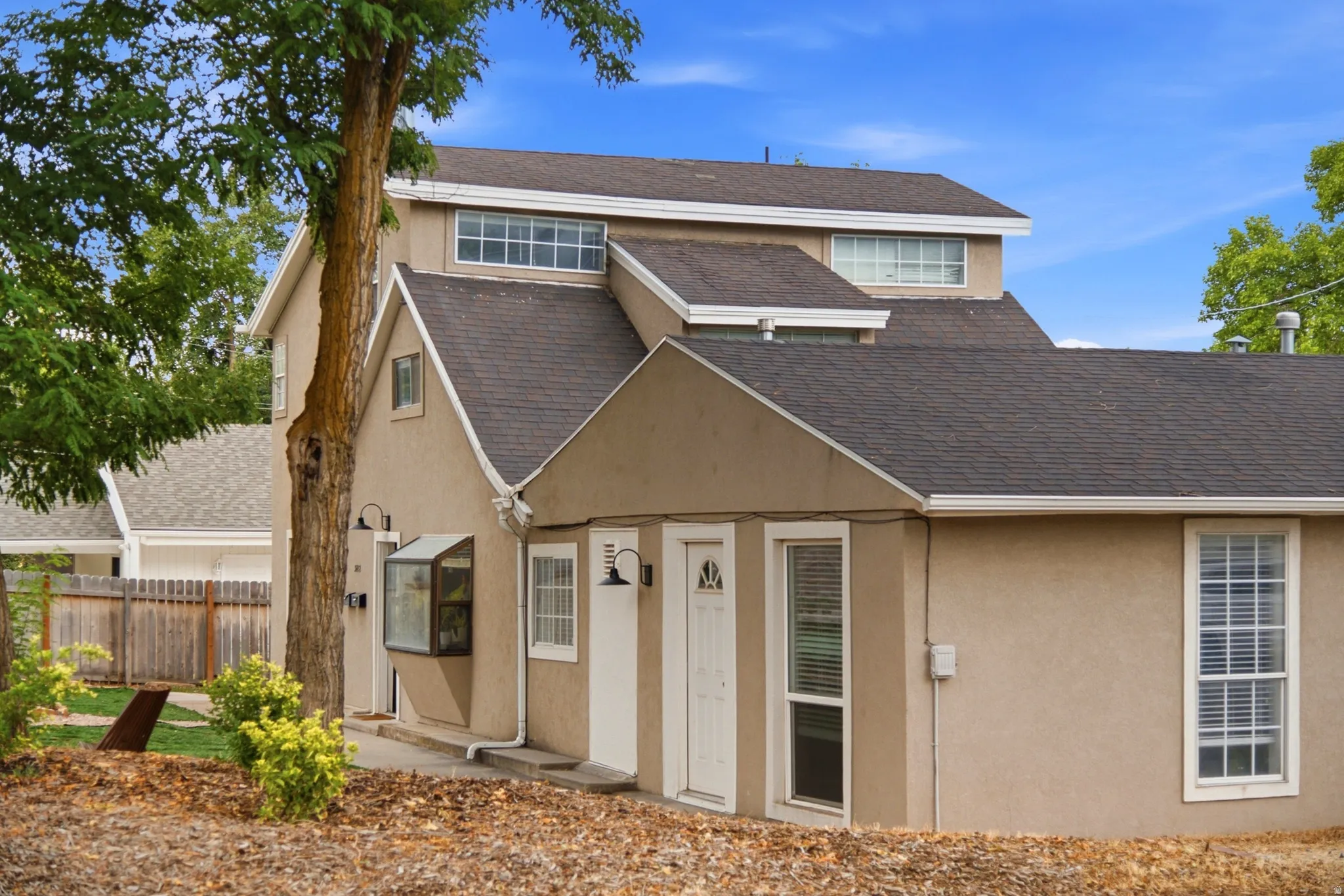 Stucco exterior with multiple rooflines, white trim, and a prominent dormer window