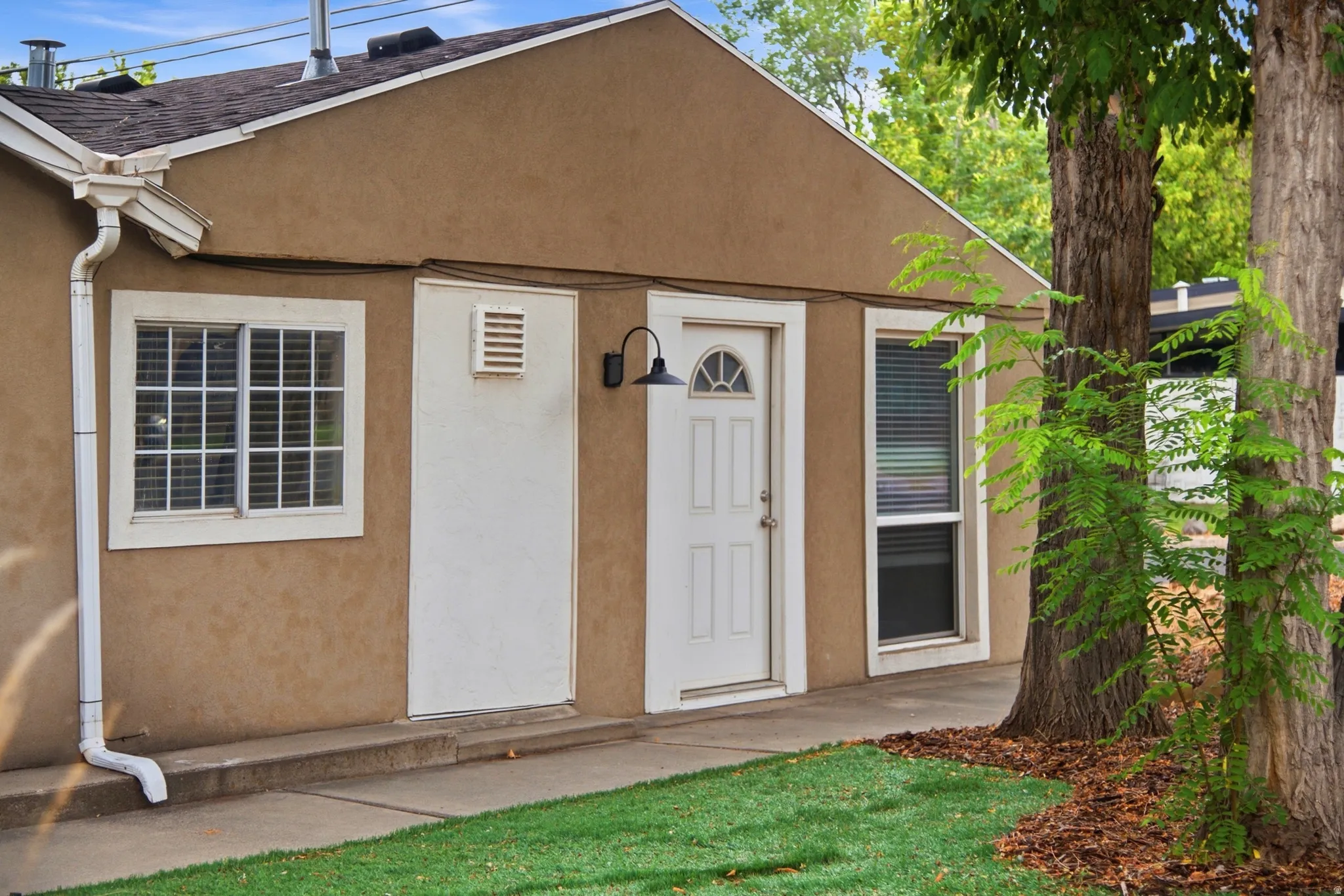 Stucco exterior with white trim, a gabled roof, and a covered entry