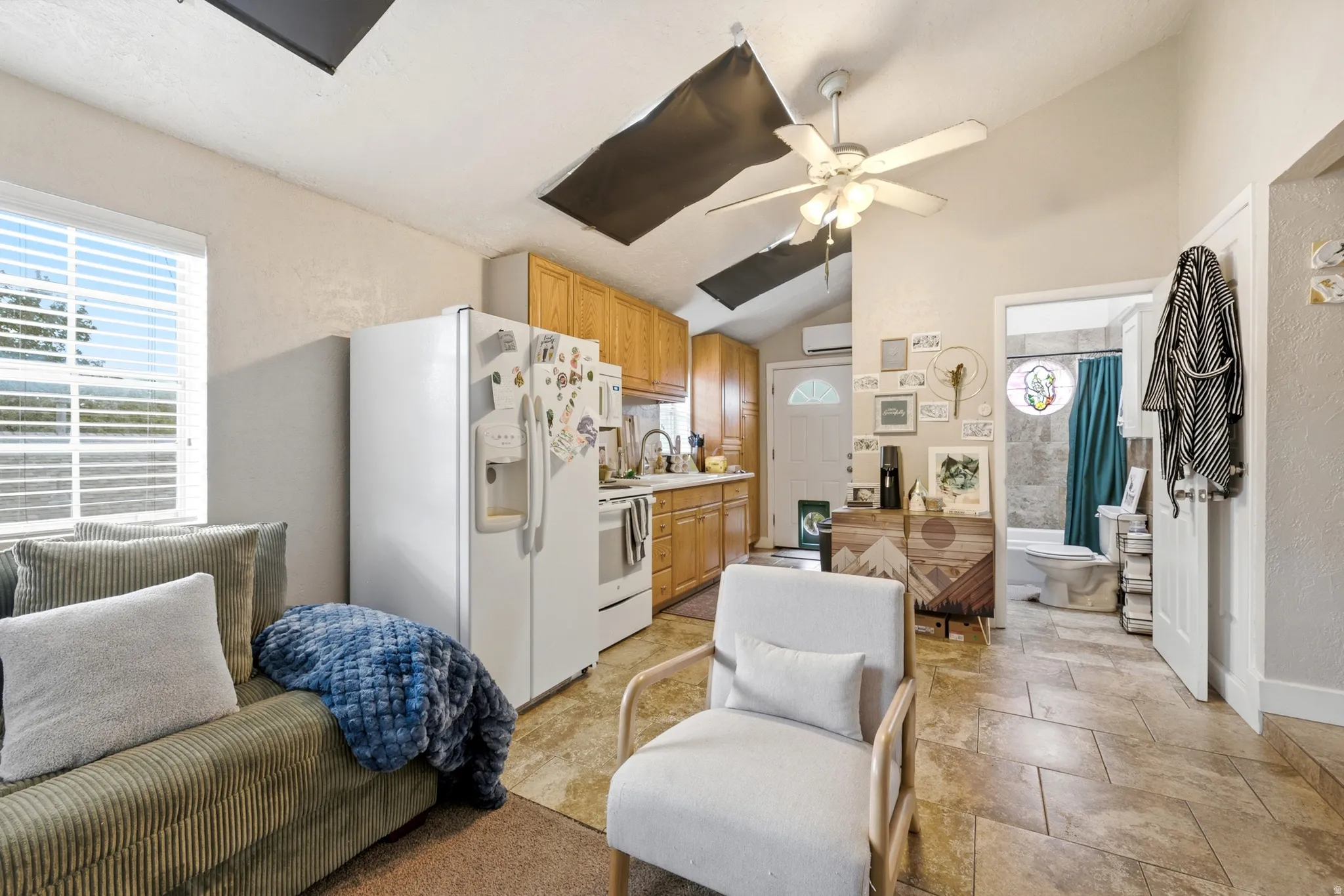 Open-concept living area featuring wood-finish flooring, ceiling fan with integrated lighting, and abundant natural light from multiple windows