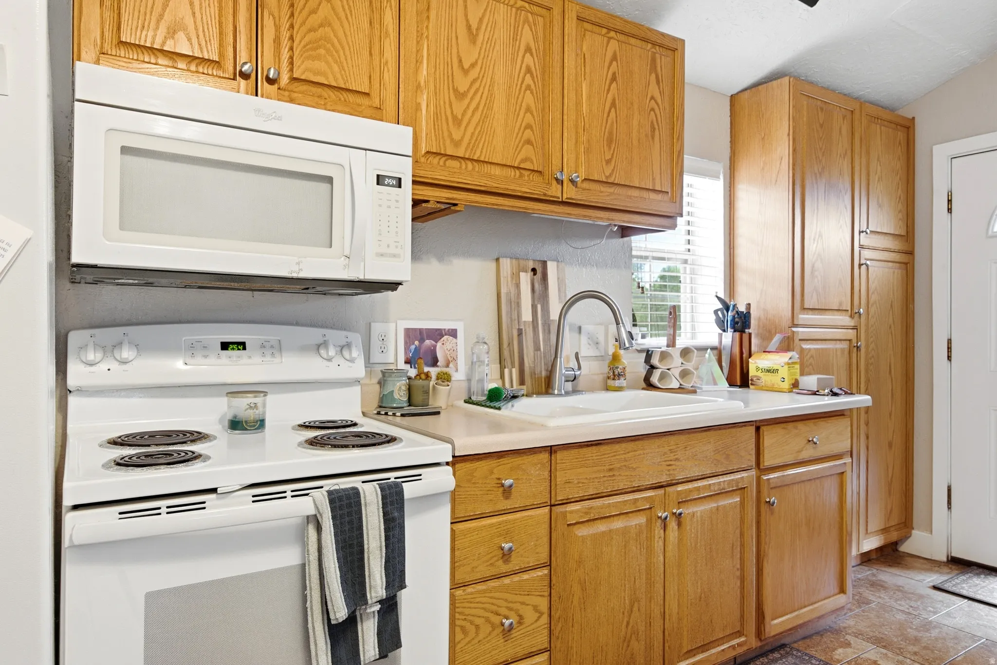 Kitchen featuring wood-finish cabinetry, white countertops, built-in microwave, and electric range