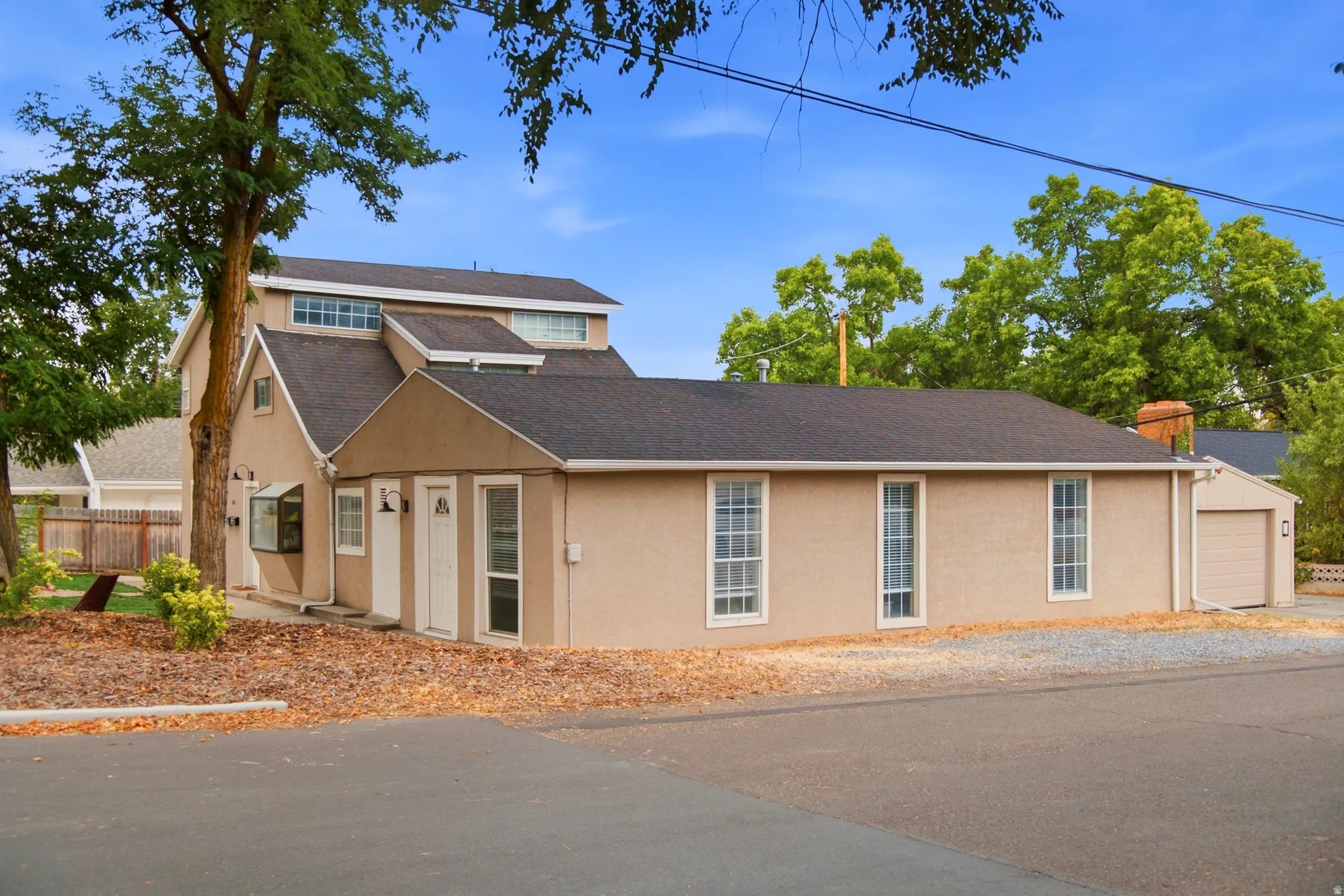 Stucco exterior with multiple rooflines, featuring a bay window, a single-car garage, and upper-level clerestory windows