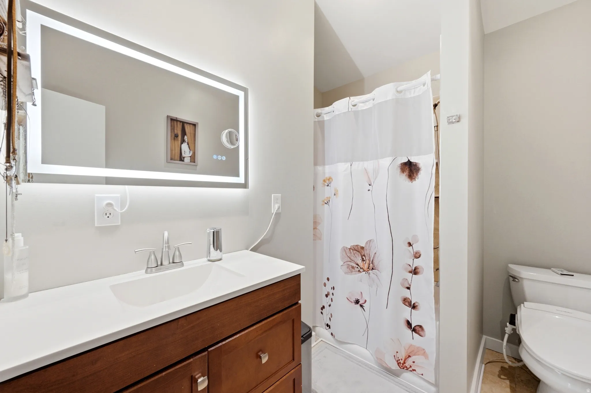 Contemporary bathroom featuring a wood-finish vanity with white countertop, chrome faucet, and integrated sink