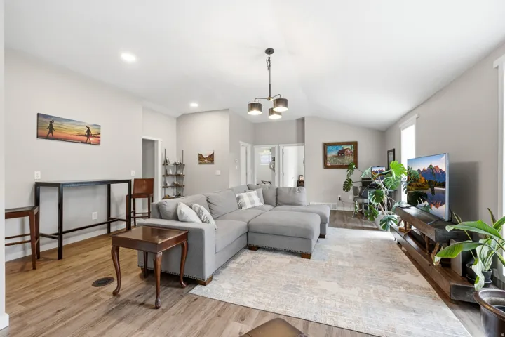 Spacious living area featuring vaulted ceilings, wood-finish flooring, and recessed lighting