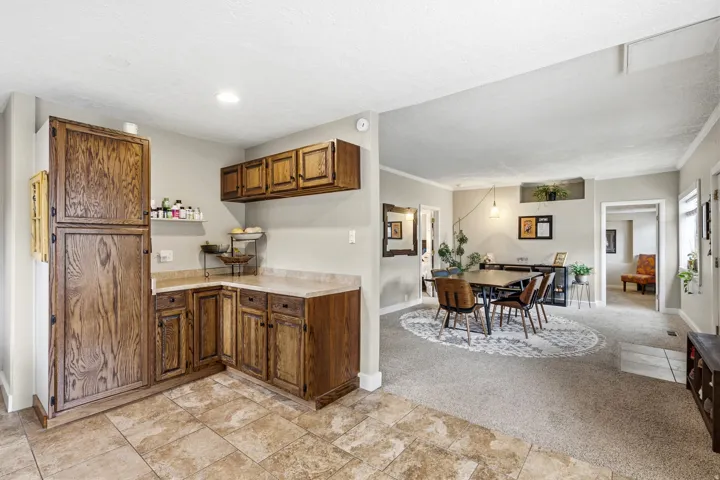 Tile flooring, wood cabinetry, light countertops, recessed lighting, and crown molding