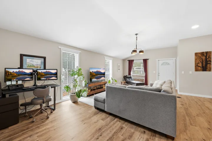 Vaulted ceiling with a contemporary chandelier, wood-finish flooring, and white trim throughout