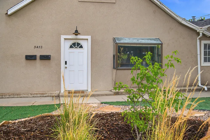 Stucco exterior featuring a white paneled entry door with an arched transom, a box window, and a gutter system