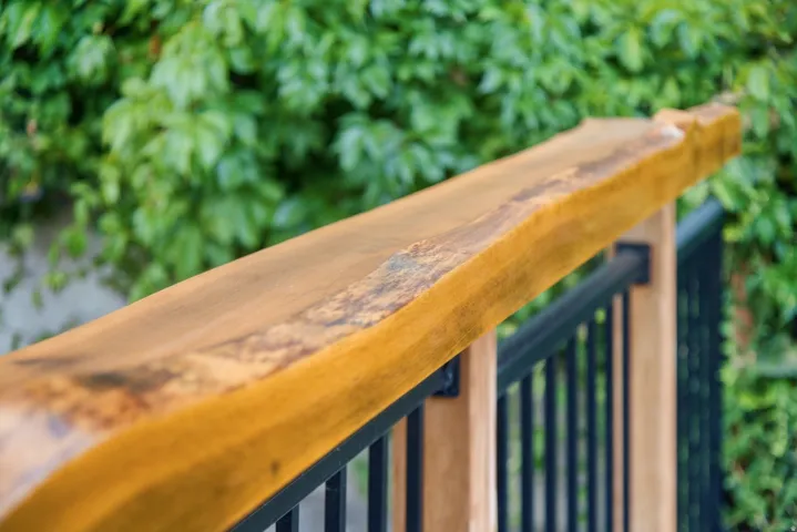 Live-edge wood railing with black metal balusters and wood posts
