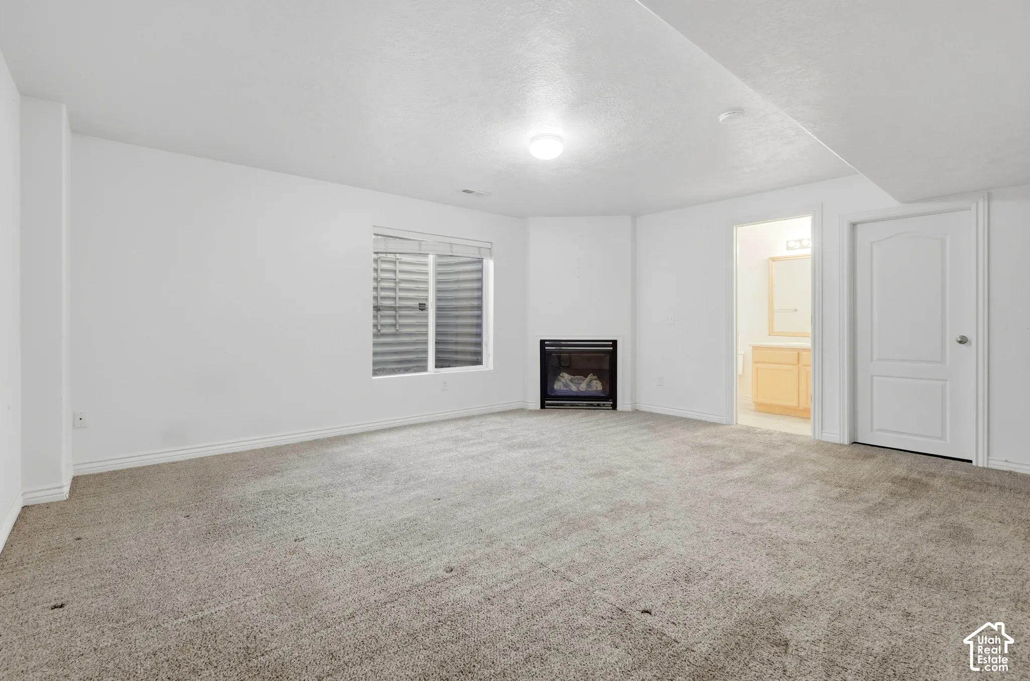 Carpeted flooring, corner fireplace, recessed window, and interior door with arched paneling