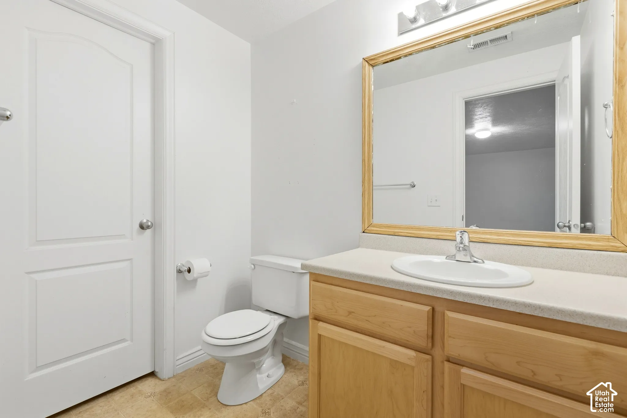 Vanity with wood-finish cabinetry, integrated sink, and laminate countertop