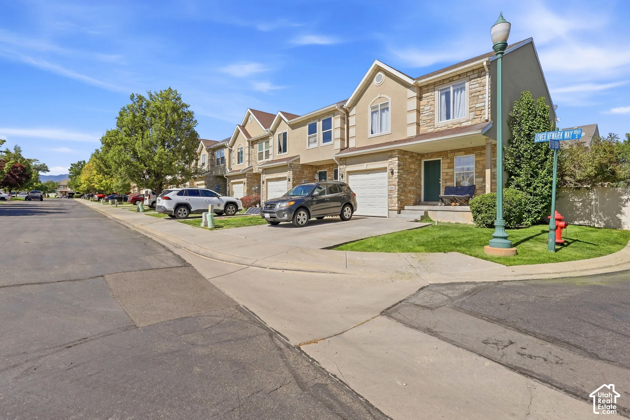 Townhouse exterior featuring a light-colored stucco finish with stone accents, an attached garage, and a covered entry