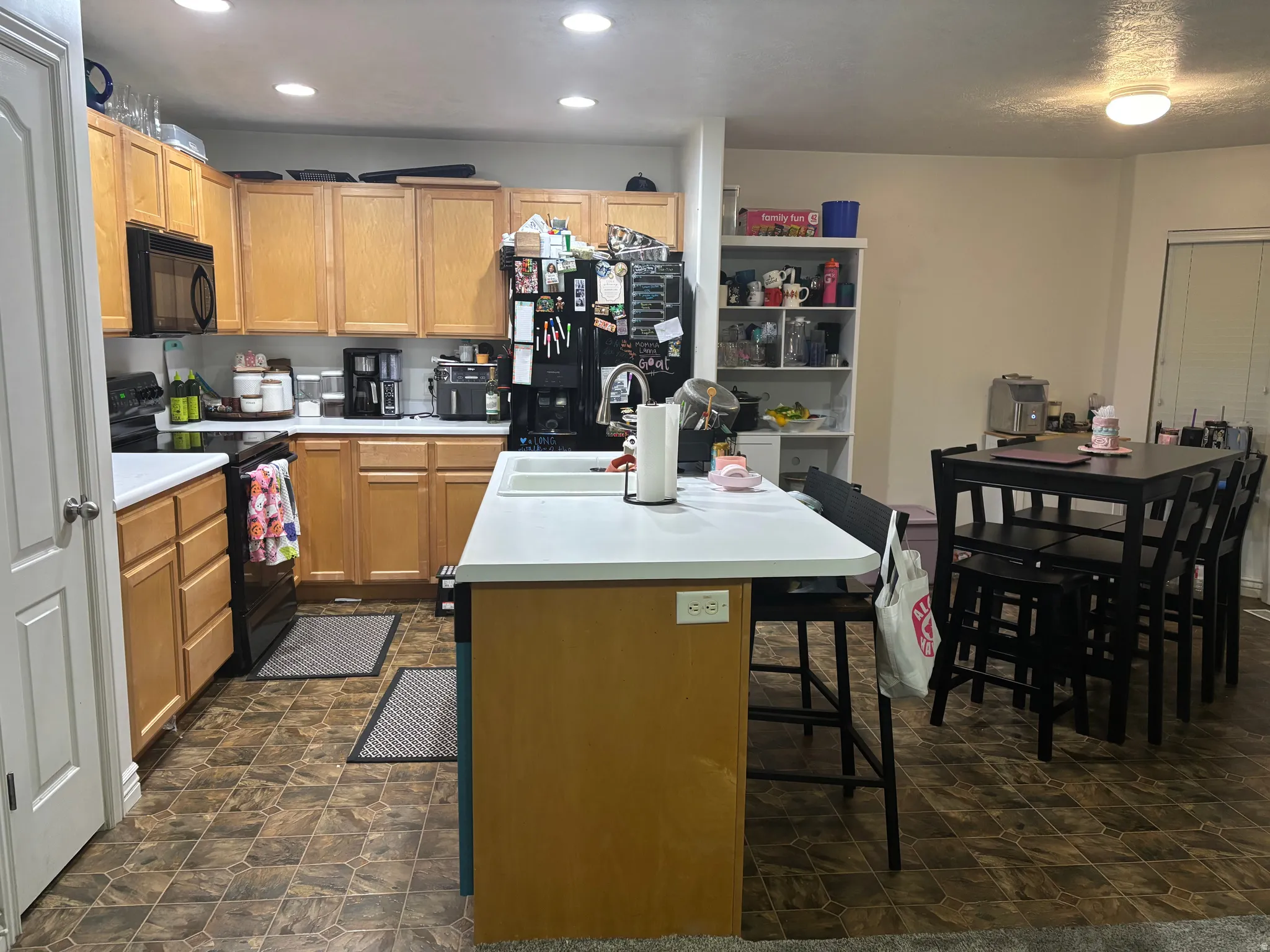 Kitchen featuring wood-finish cabinetry, white countertops, black appliances, and recessed lighting