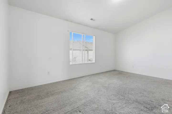 Neutral gray carpeting with white walls, featuring a window with white blinds