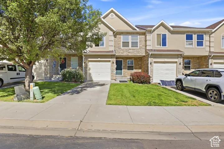 Stone and stucco exterior with multiple windows, an attached garage, and a concrete driveway