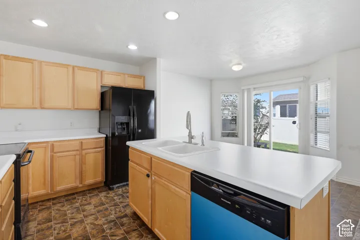 Light wood cabinetry with white countertops, black appliances, and a double basin sink with a high arc faucet