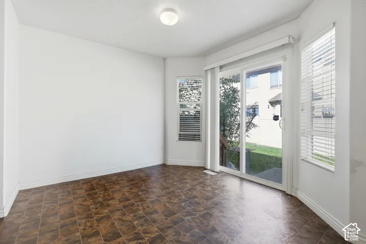 White walls featuring a sliding glass door, multiple windows with horizontal blinds, and patterned tile flooring