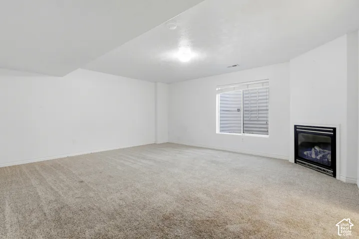 Recessed fireplace with a black insert, light-toned carpeting, and a window with blinds