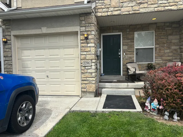 Stone veneer facade with a paneled garage door and an entry door