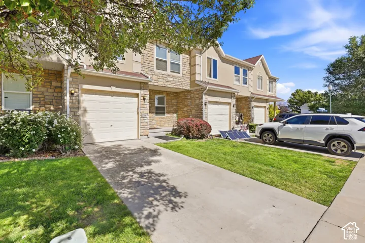 Stone and stucco exterior with multiple single-car garages, mature landscaping, and concrete driveways