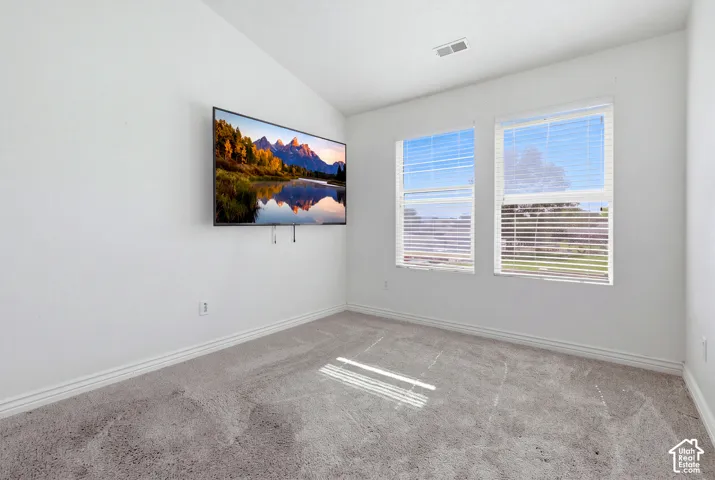 White walls, two windows with blinds, and light-toned carpeting