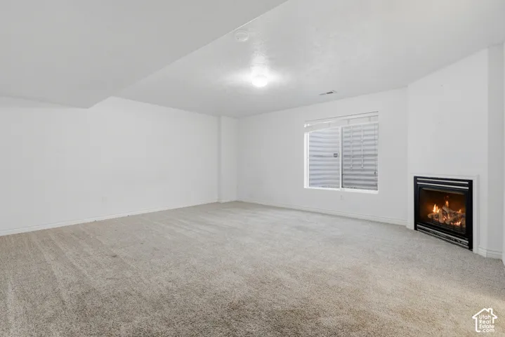 Recessed fireplace with black surround, soft carpet flooring, and a single window