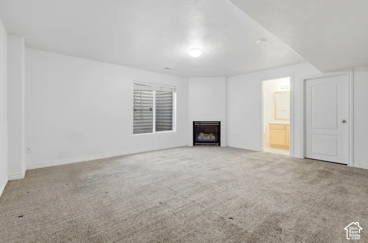Carpeted flooring, corner fireplace, recessed window, and interior door with arched paneling