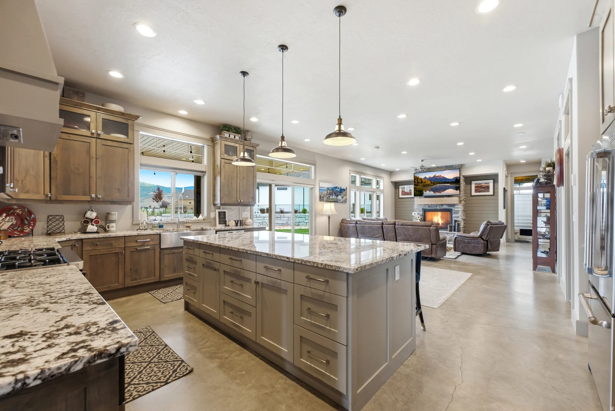 Expansive kitchen island with stone countertop, stainless steel appliances, and recessed lighting