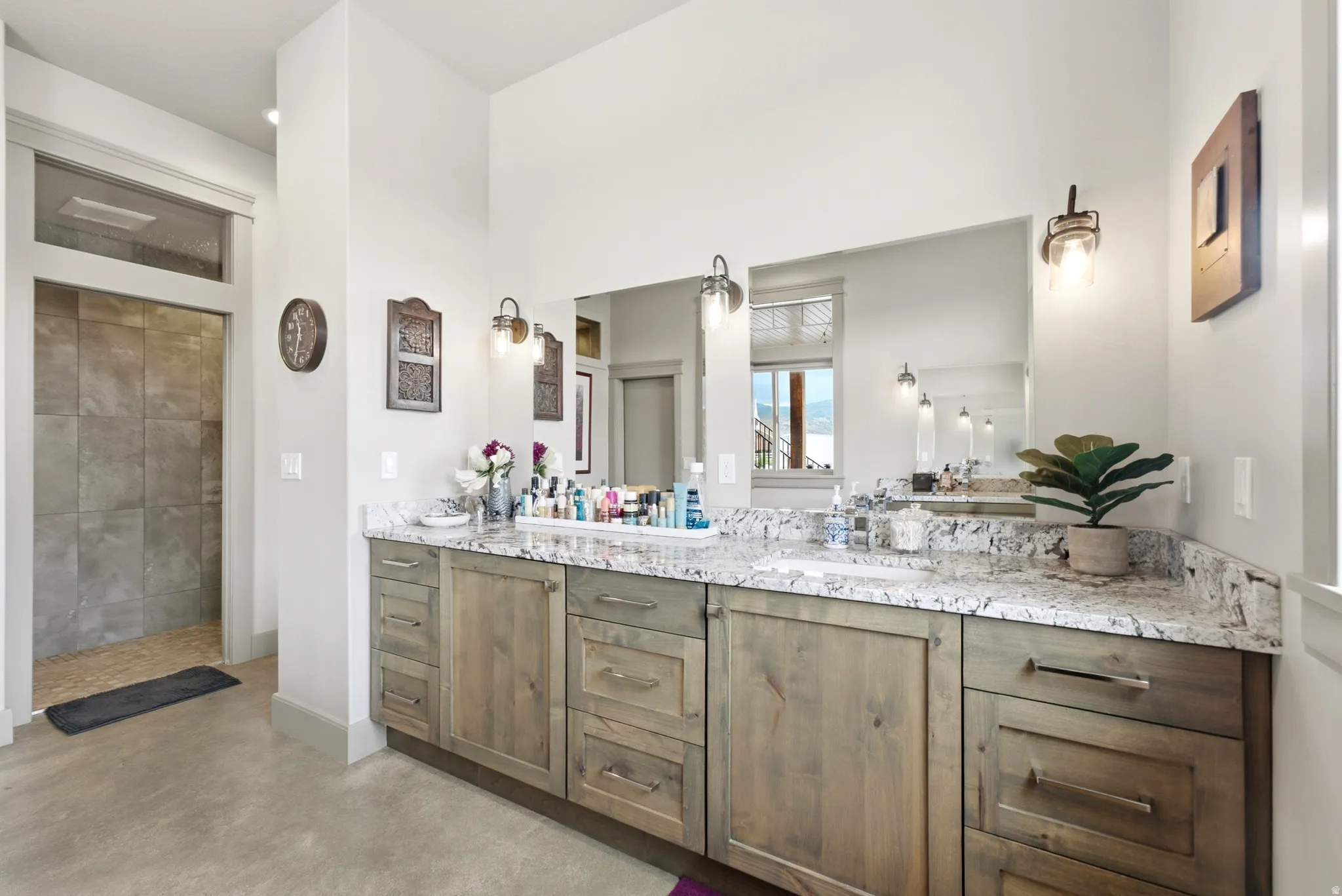 Dual vanity with wood-finish cabinetry, granite-style countertop, and integrated sinks