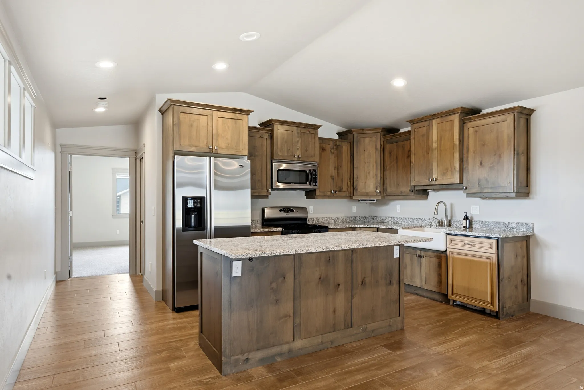 Kitchen featuring wood-finish flooring, recessed lighting, wood cabinetry, stone countertops, and stainless steel appliances