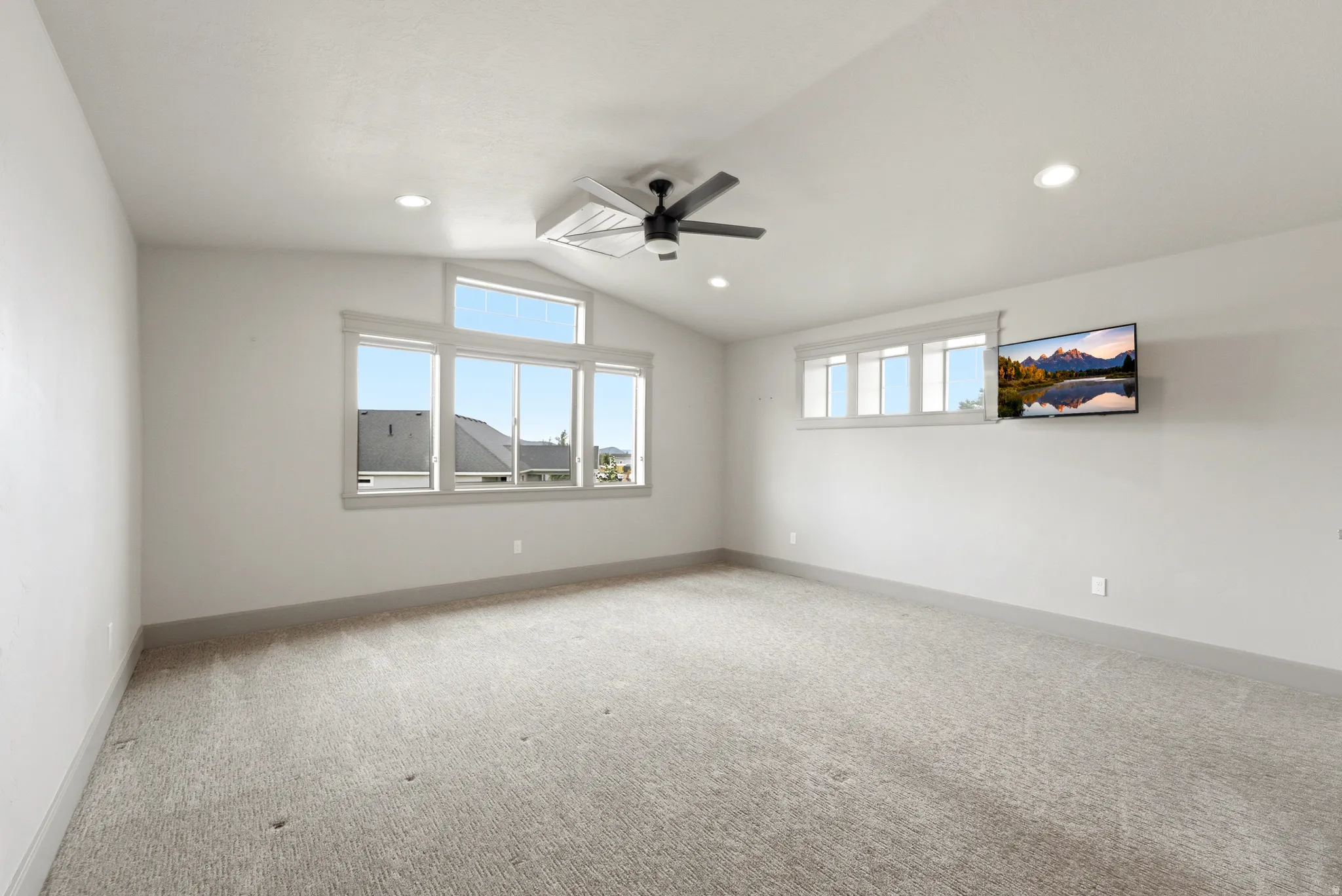 Vaulted ceiling with a contemporary ceiling fan, recessed lighting, expansive windows, and light-toned carpeting