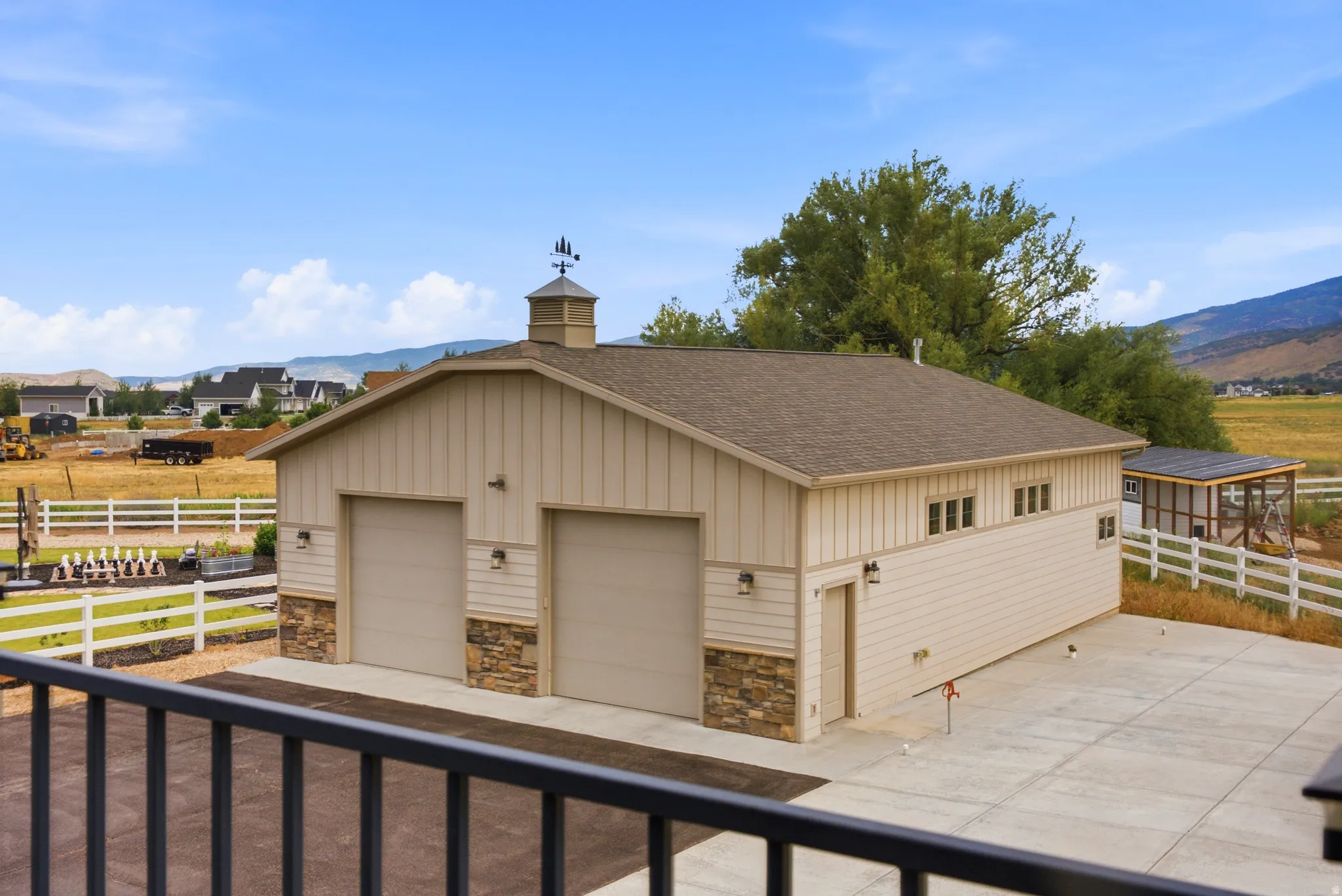 Detached multi-car garage with two overhead doors, cupola, board-and-batten siding, and stone accents