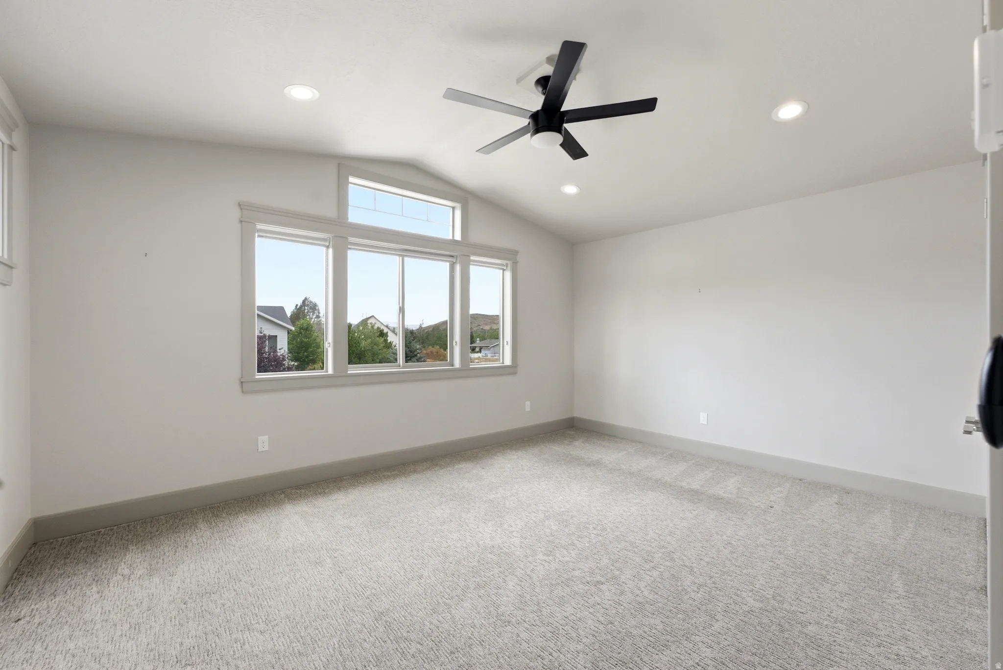 Vaulted ceiling with an integrated ceiling fan, recessed lighting, and large windows with transom architectural details