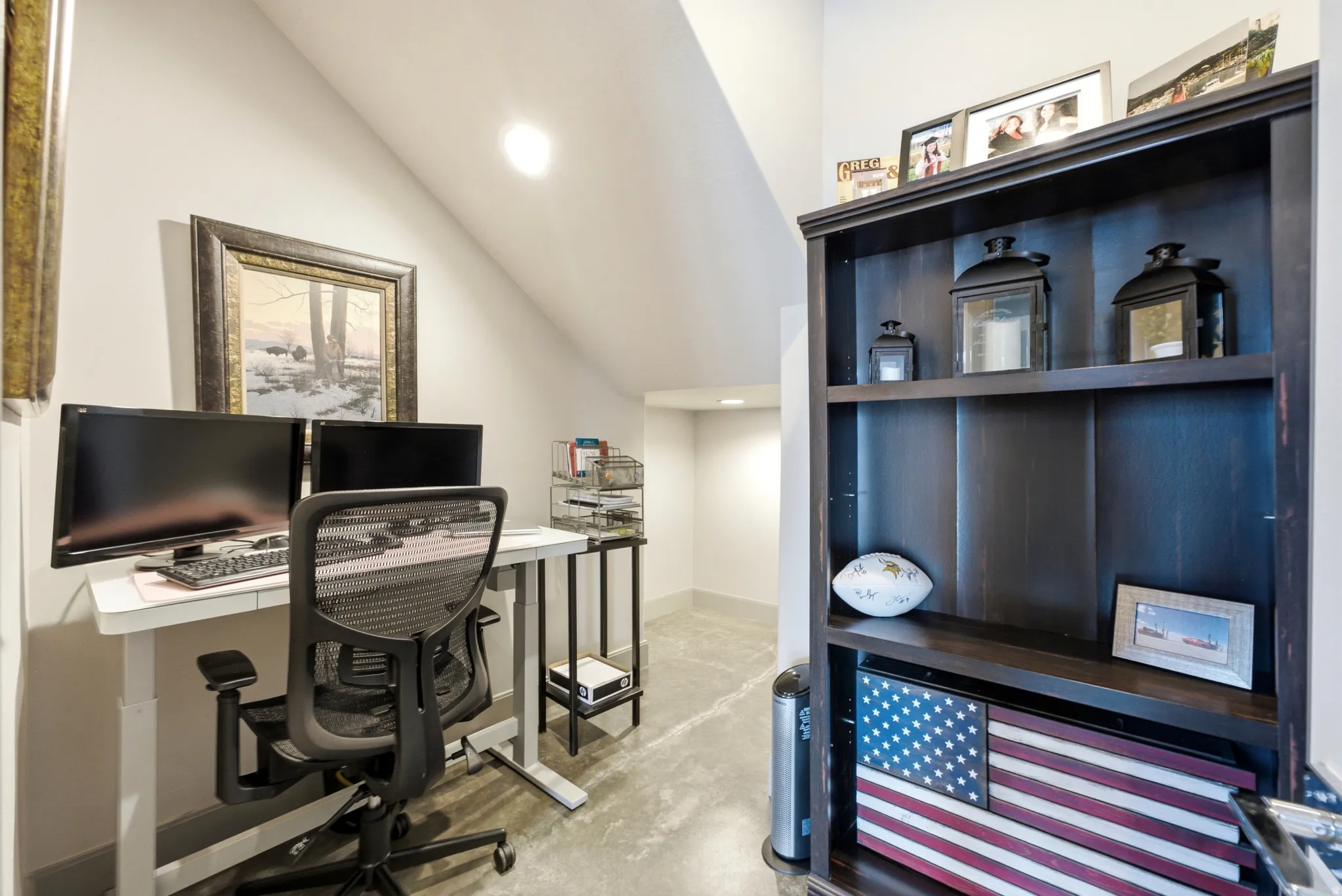Sloped ceiling architecture, recessed ceiling lighting, dark wood finish built-in shelving, concrete flooring, and light wall tones