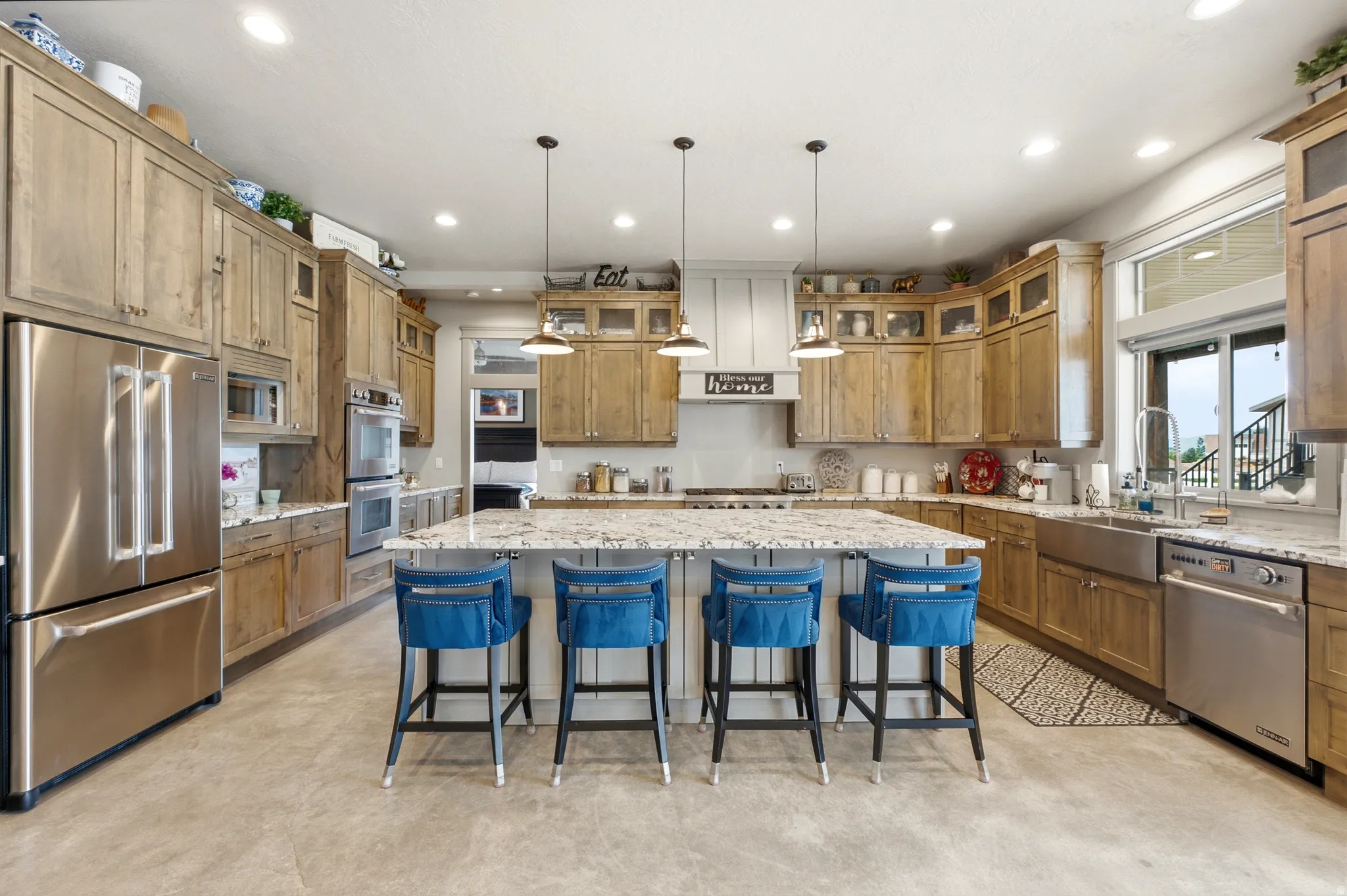 Chef's kitchen featuring custom wood cabinetry, stainless steel appliances, and a spacious island with seating for four