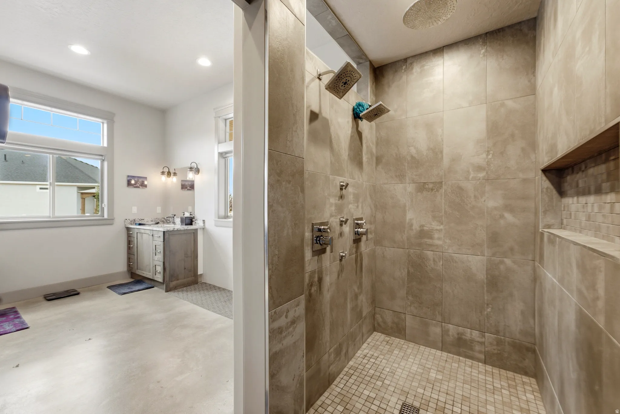 Spa-inspired primary bathroom featuring a spacious walk-in shower with multiple showerheads, neutral tile surround, and built-in niches