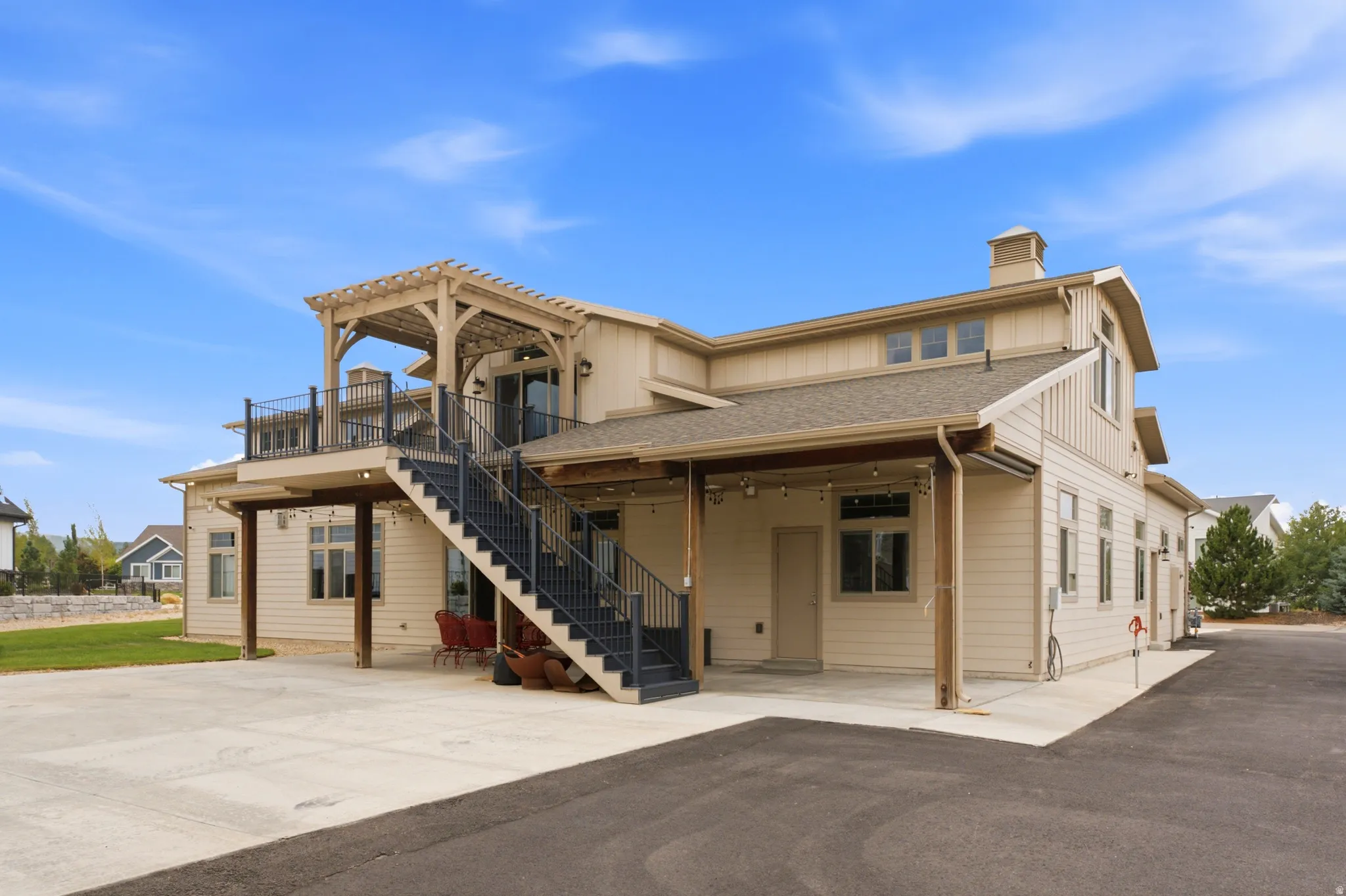 Exterior showcasing a second-story balcony with pergola, an exterior staircase with metal railings, and a ground-level patio