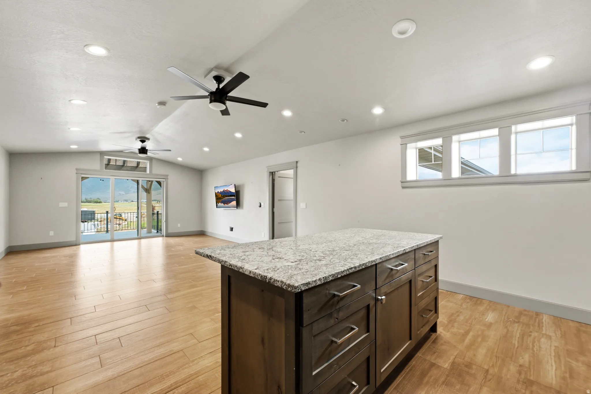 Spacious room featuring wood-finish flooring, recessed lighting, and modern ceiling fans