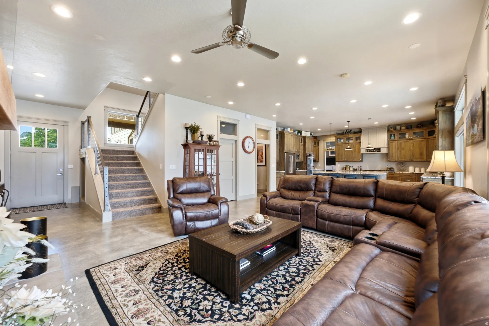Open concept living area with recessed lighting, ceiling fan, and staircase with metal railings