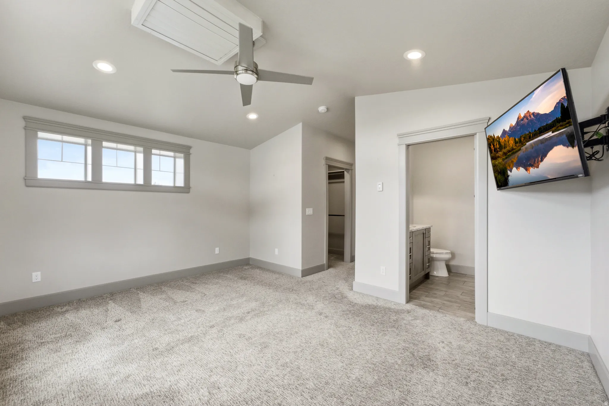Recessed lighting, ceiling fan, triple transom window, and an en suite bathroom with a vanity and toilet