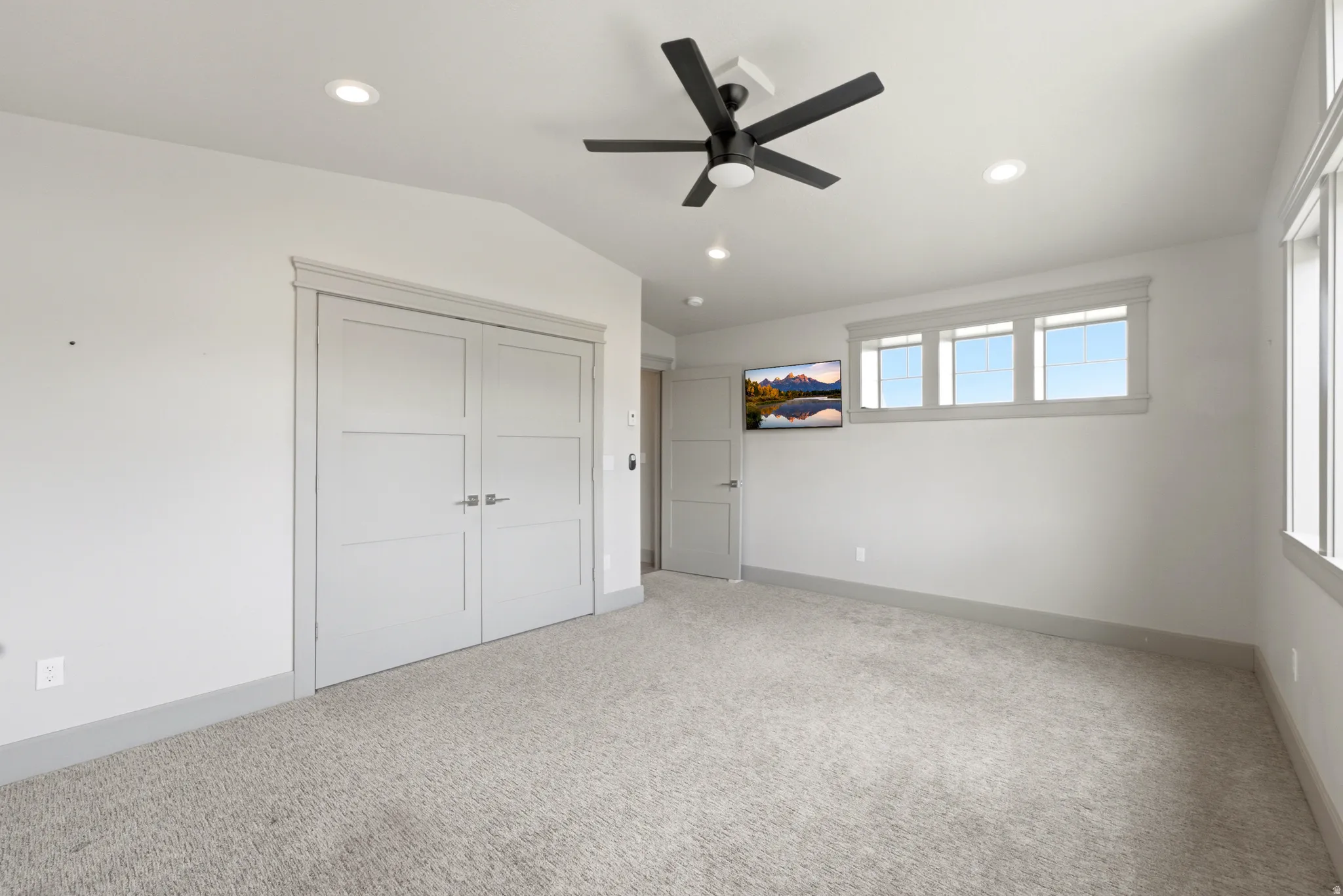 Carpeted room with a vaulted ceiling, recessed lighting, a ceiling fan, and multiple windows