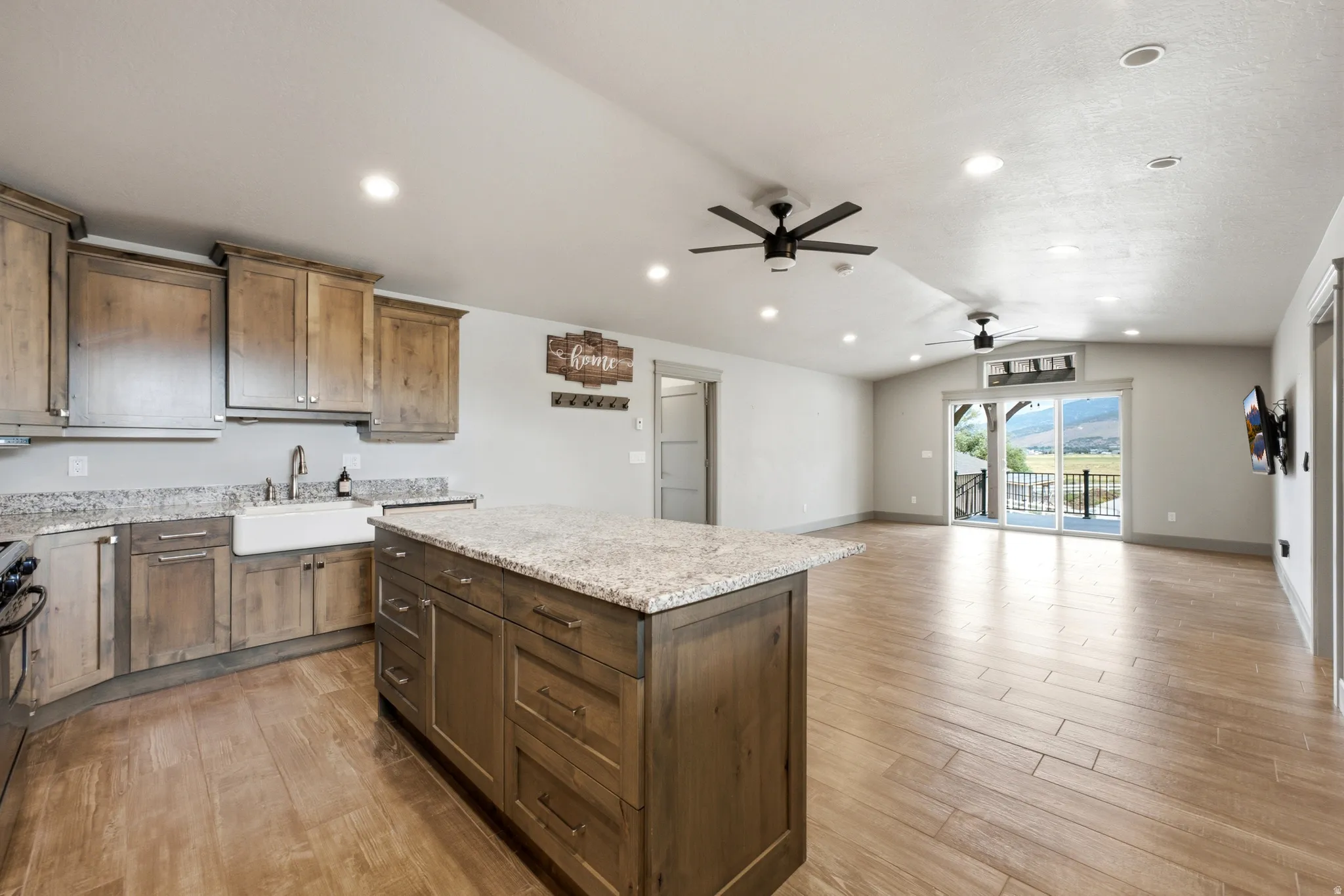 Open-concept living space with wood-finish flooring, recessed lighting, and ceiling fans