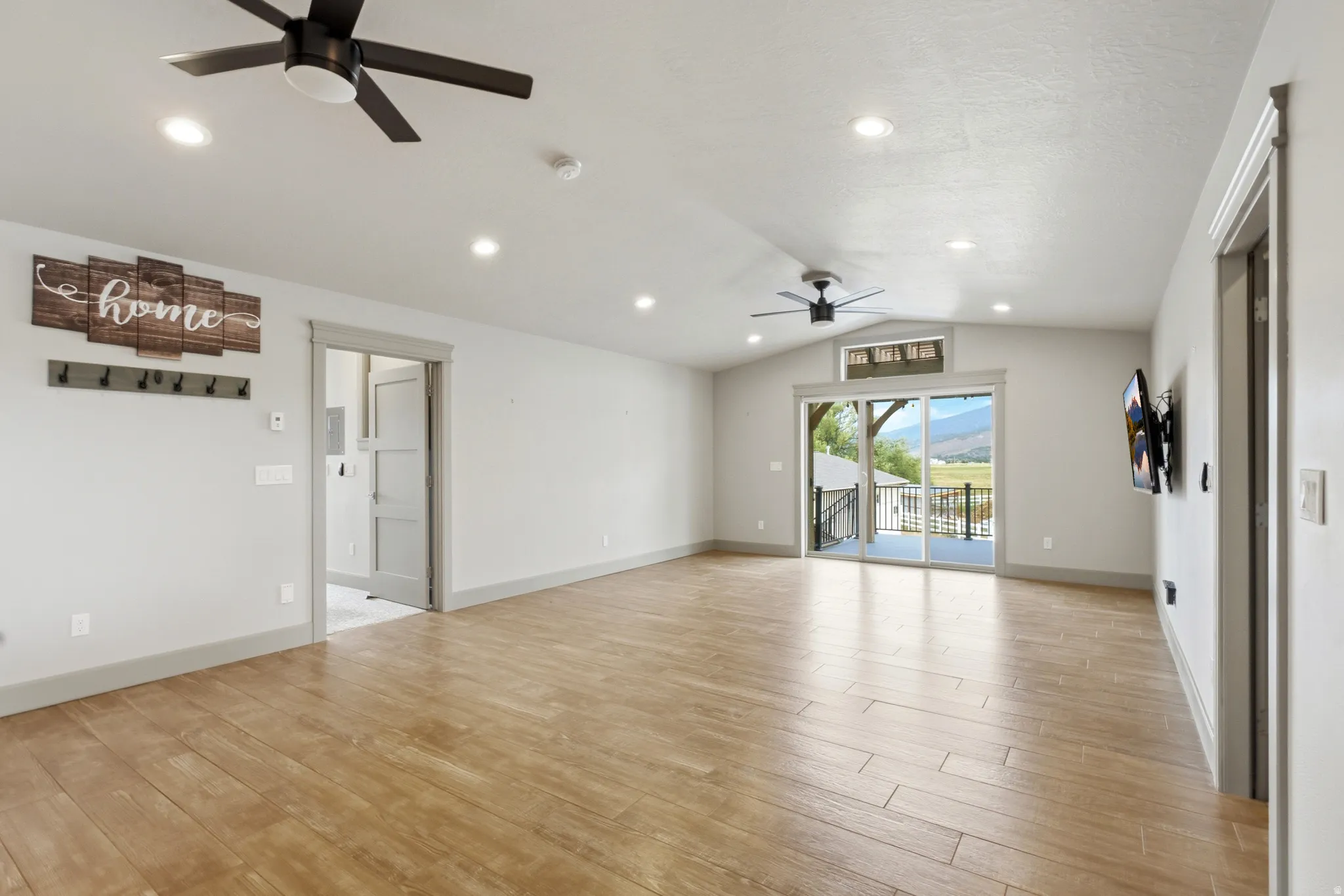 Spacious room with wood-finish flooring, recessed lighting, and ceiling fans