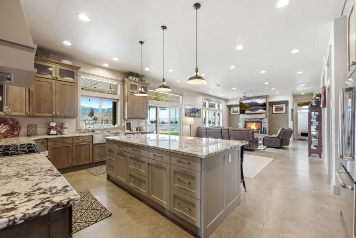 Expansive kitchen island with stone countertop, stainless steel appliances, and recessed lighting