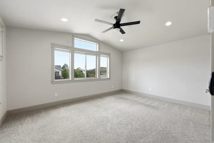 Vaulted ceiling with an integrated ceiling fan, recessed lighting, and large windows with transom architectural details