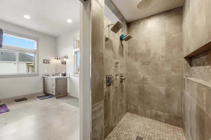 Spa-inspired primary bathroom featuring a spacious walk-in shower with multiple showerheads, neutral tile surround, and built-in niches