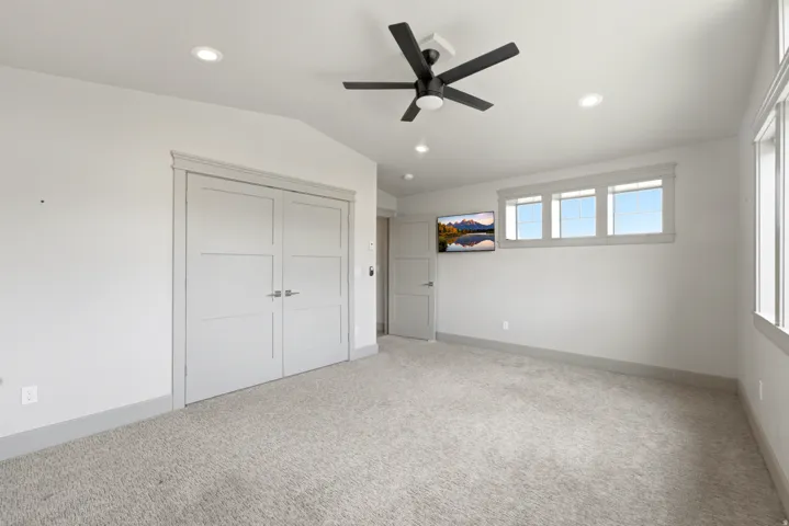 Carpeted room with a vaulted ceiling, recessed lighting, a ceiling fan, and multiple windows