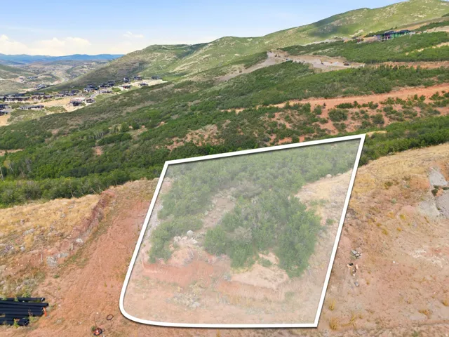 Elevated building site featuring natural vegetation and expansive mountain terrain